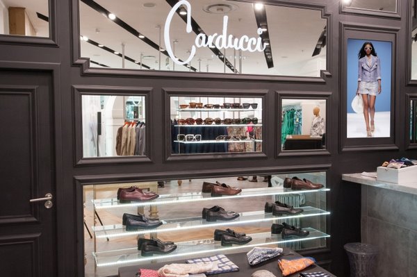 Бутик Carducci, Кейптаун. Зеркало в прикассовой зоне подчеркивает цветовую гармонию обуви и одежды, расположенных по разным стенам магазина